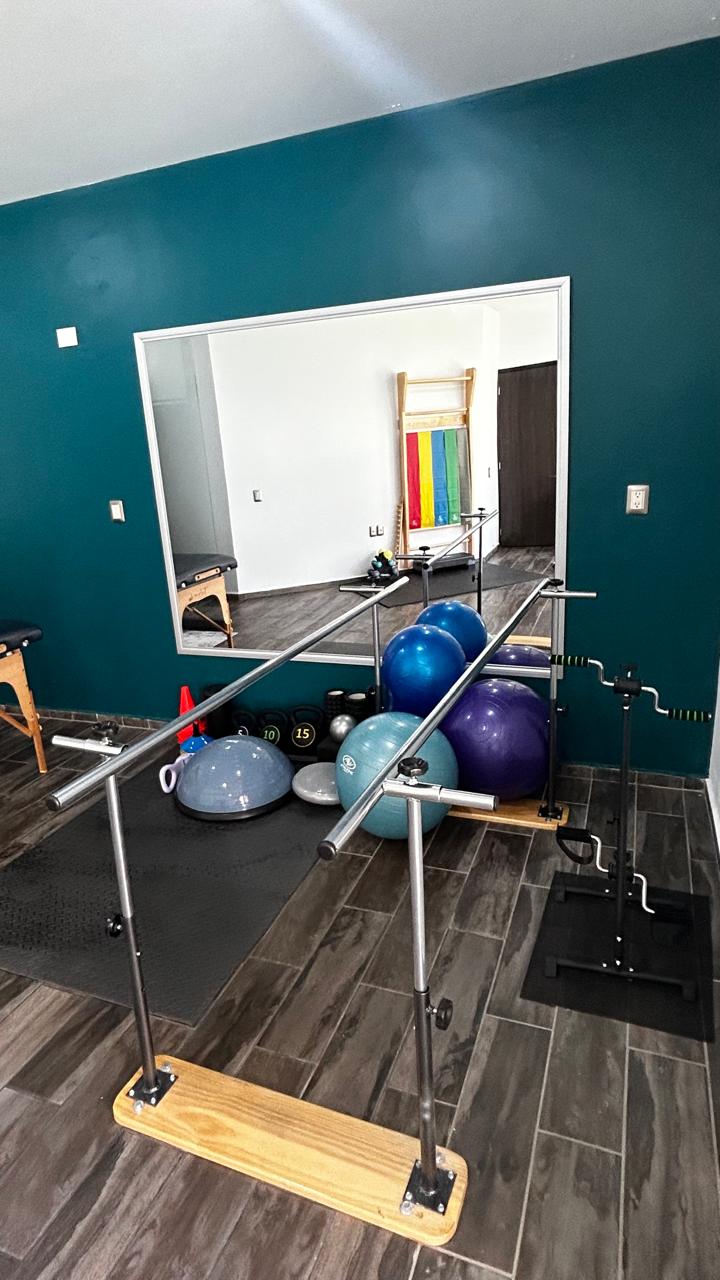 Área de rehabilitación con barras paralelas y equipo profesional